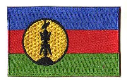 New Caledonia flag patch, featuring Kanak flag design with blue, red, green stripes, and yellow disc. Size: 6.5 x 4 cm.